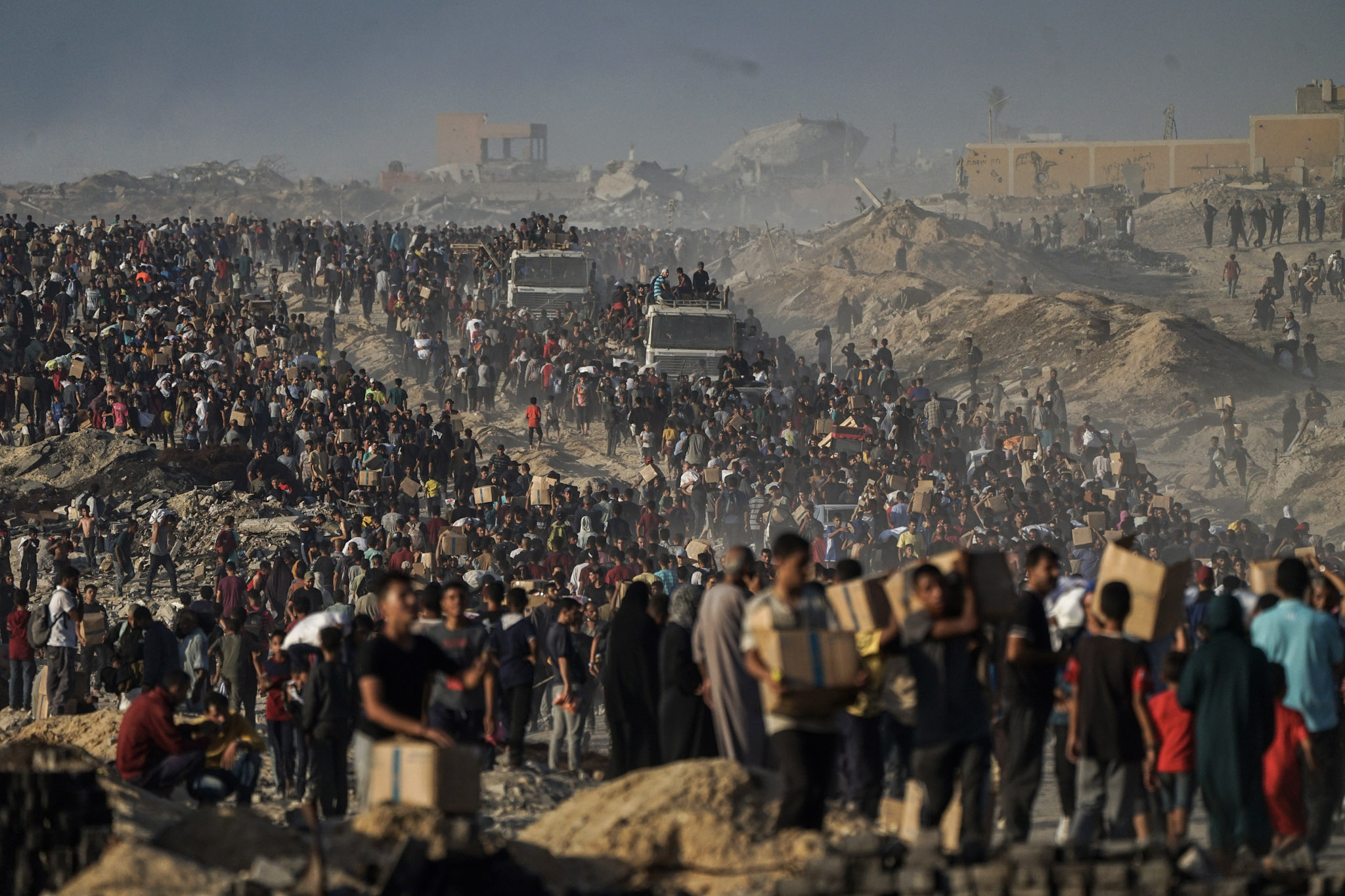 Palestinos transportan sacos y cajas de alimentos y ayuda humanitaria descargados de un convoy del Programa Mundial de Alimentos que se dirigía a la ciudad de Gaza, en el norte de la Franja de Gaza, el lunes 16 de junio de 2025.