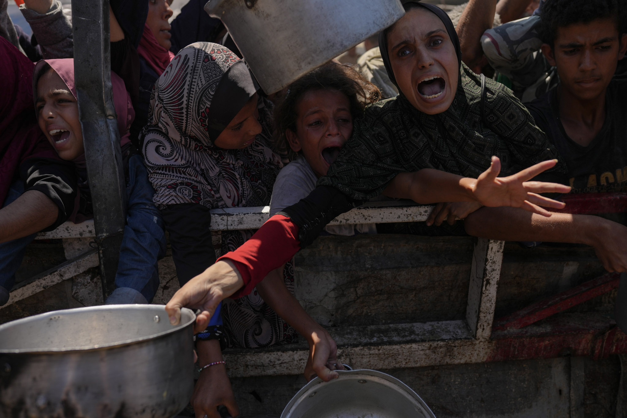 Los palestinos luchan por recibir alimentos donados en una cocina comunitaria en la ciudad de Gaza, el lunes 4 de agosto de 2025.