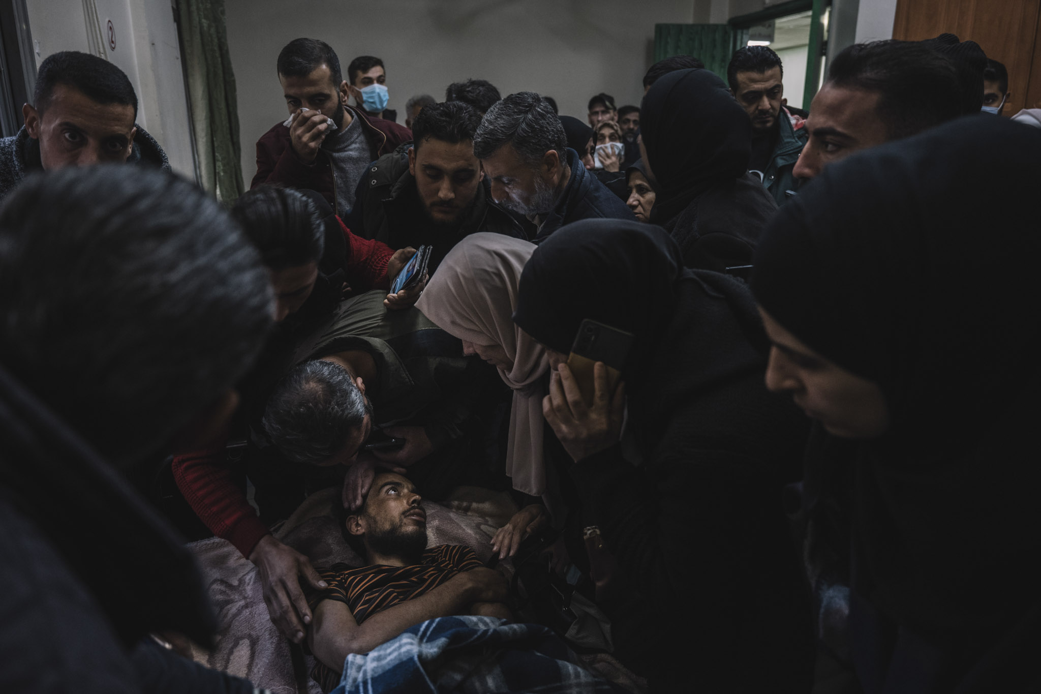 Decenas de personas se agolpan alrededor de este prisionero trasladado. Las familias que buscan a sus seres queridos rodean a un prisionero que fue trasladado al hospital Ibn Al-Nafis de Damasco. No puede pronunciar su propio nombre, pero todos los que le rodean quieren que diga otros nombres. Es uno de los innumerables prisioneros torturados en la cárcel de Sednaya, en las afueras de Damasco. Cuando cayó el régimen de Bashar al-Assad, él y otros supervivientes fueron trasladados a varios hospitales de Damasco. Ahora se está recuperando en una de sus habitaciones, pero no puede descansar. Una multitud se agolpa a su alrededor, agitando teléfonos, mostrándole vídeos y fotos. Son familiares de otros presos. Le preguntan si reconoce a alguien en las imágenes. Él no responde: su mirada busca rostros, formas, pistas, pero no encuentra nada. Las docenas de personas desesperadas que rodean su camilla forman un muro humano impenetrable para los médicos e incluso para las nuevas autoridades militares. Nadie los sacará de allí.