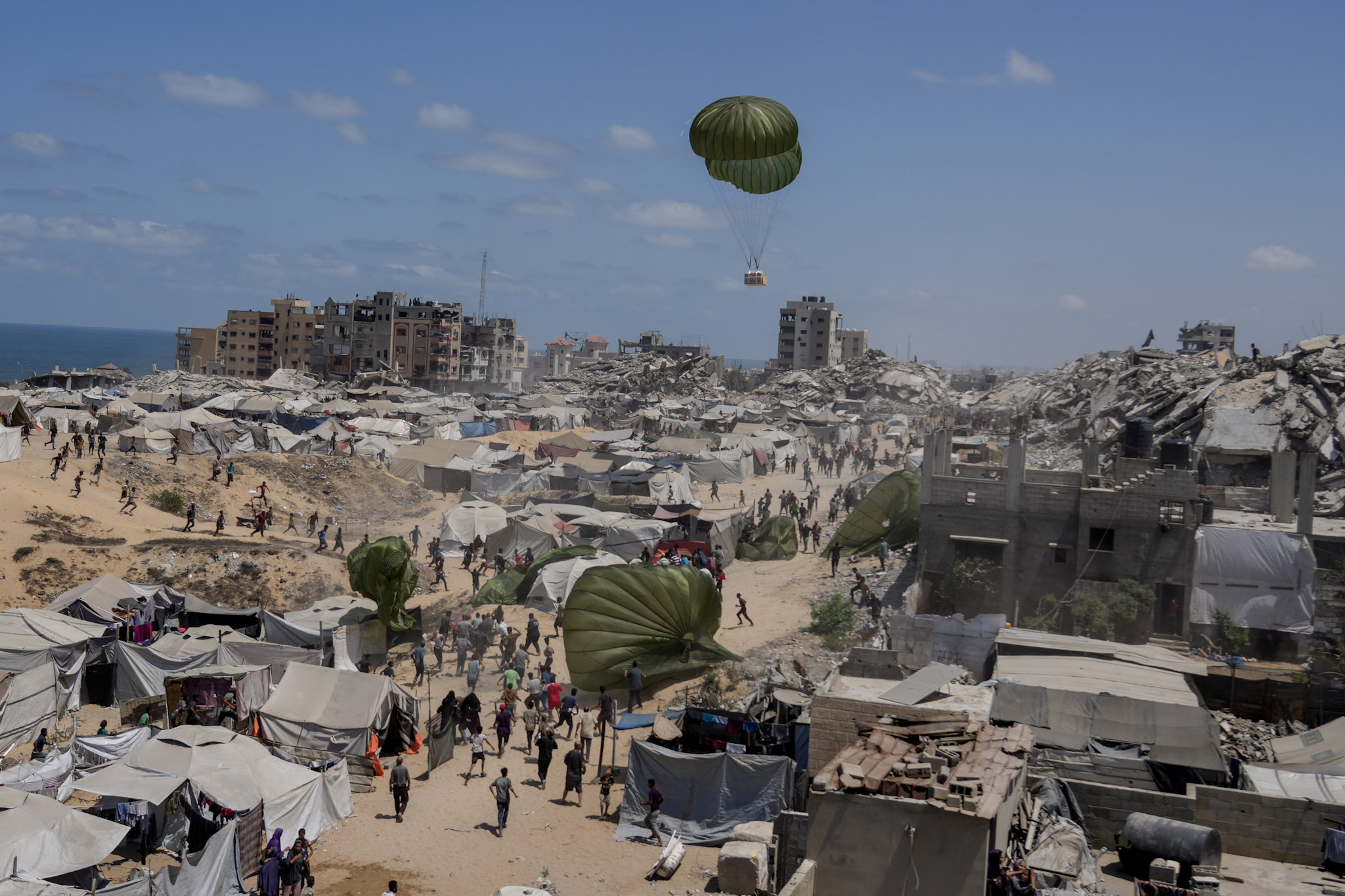 Los palestinos se apresuran a recoger la ayuda humanitaria lanzada en paracaídas sobre la ciudad de Gaza, en el norte de la Franja de Gaza, el 7 de agosto de 2025.